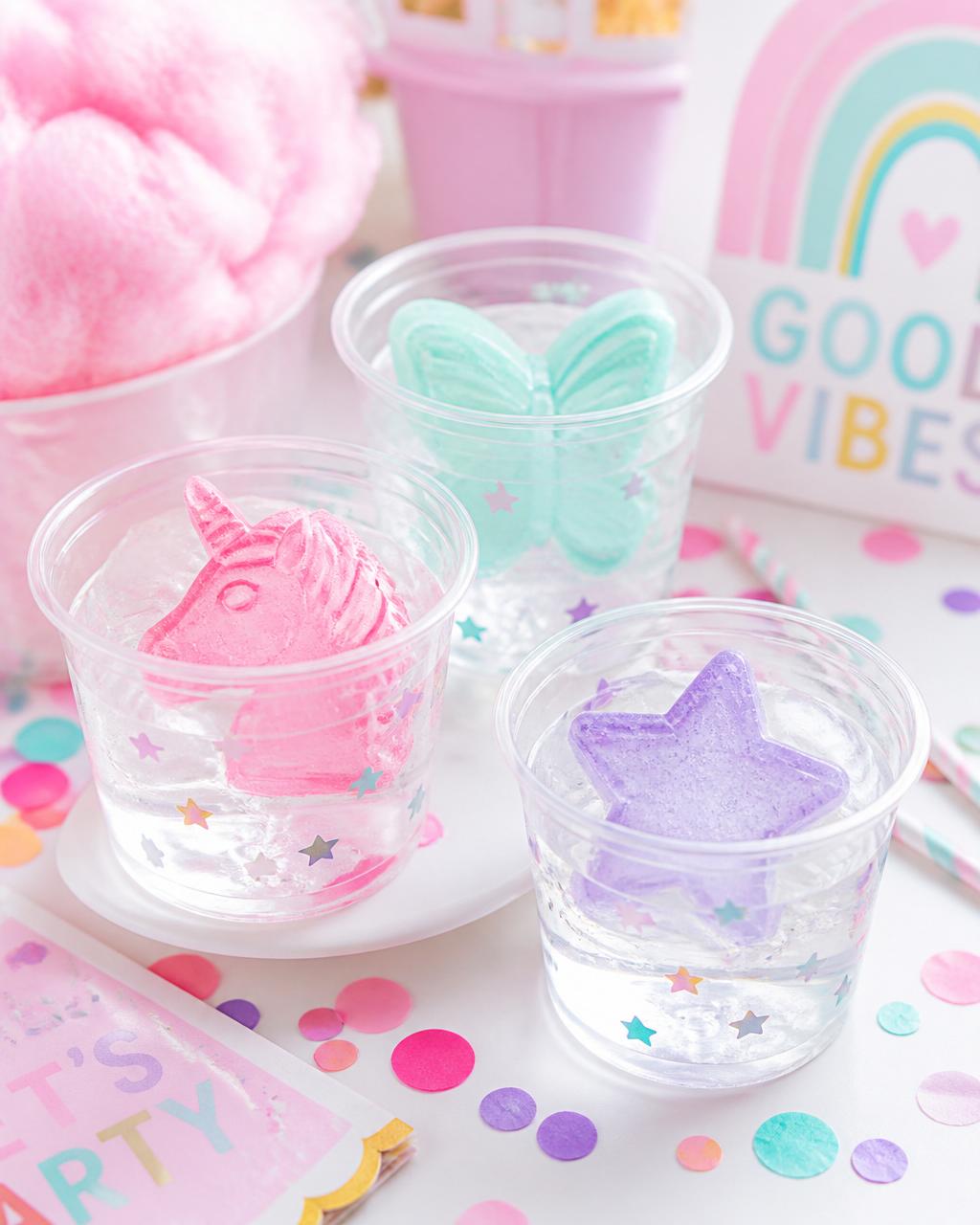 Fête™ Pastel party ice collection Glacée Fête colorful pastel party ice — pink unicorn, mint butterfly, and lavender star shapes in clear cups surrounded by confetti